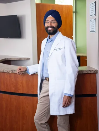 A man in white coat standing next to a counter.